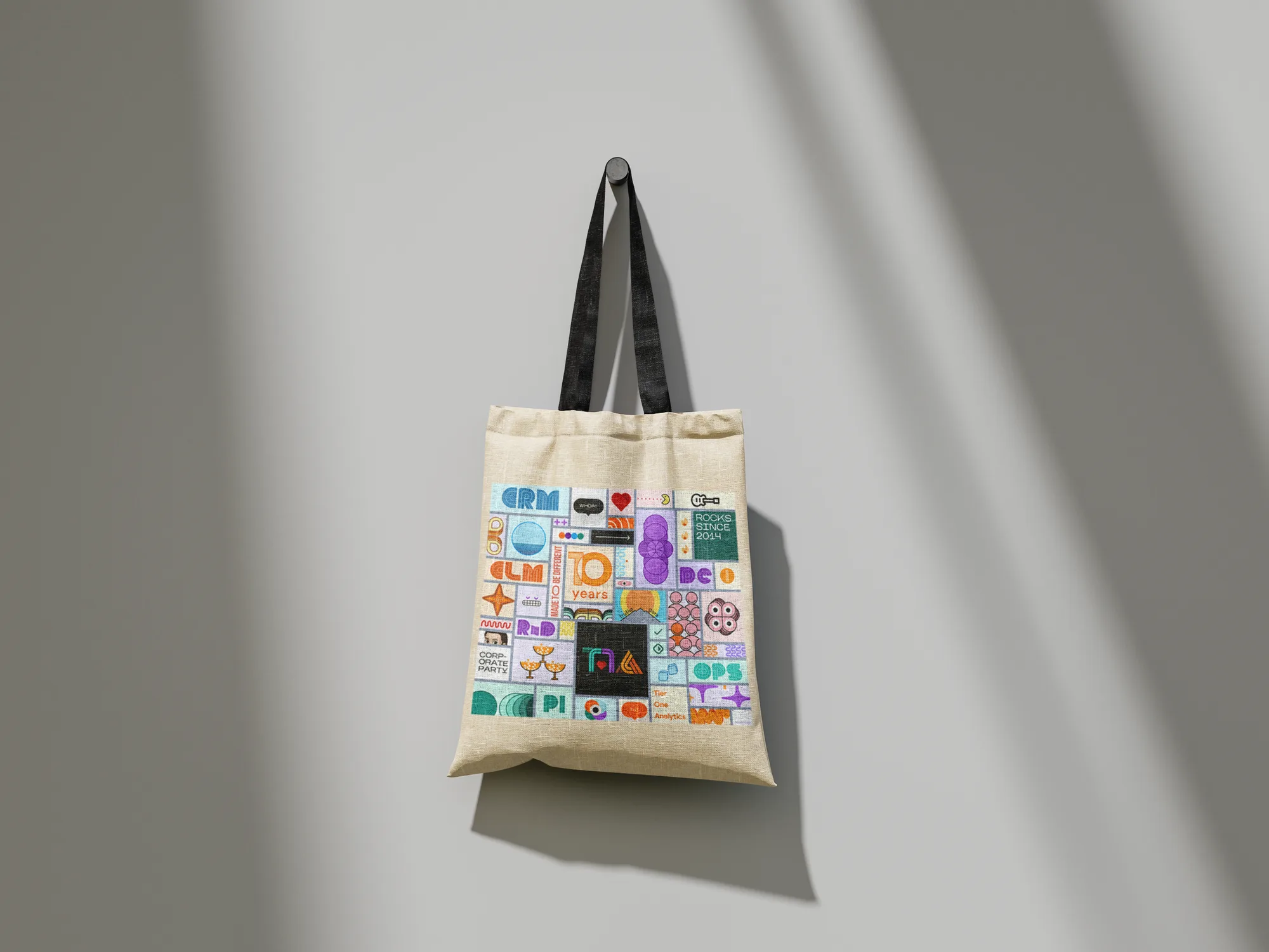 Hanging tote bag covered in the T1A anniversary illustrations
